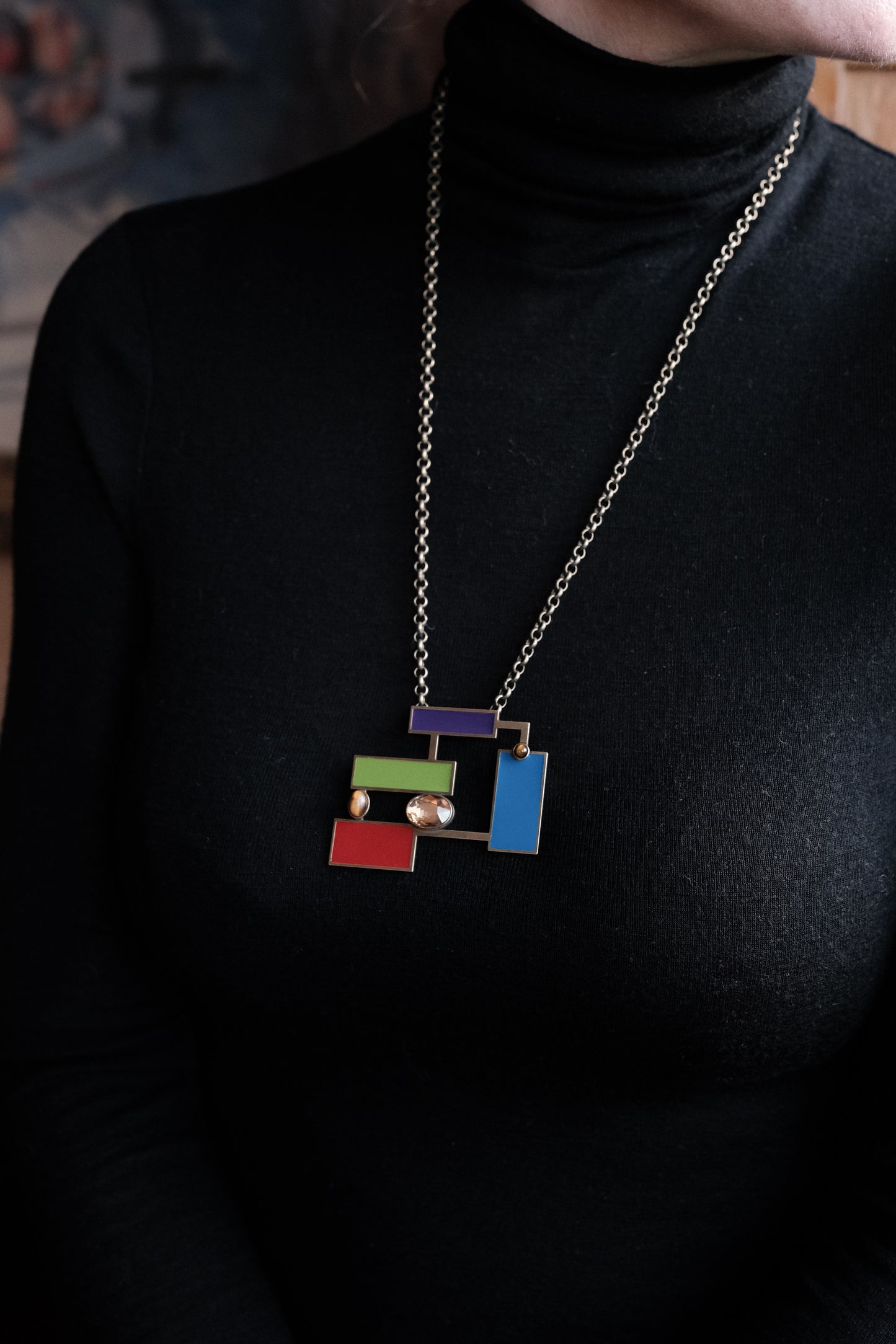 Stylish Suzanne Tiger's eye brooch pendant displayed on a model wearing a black turtleneck, showcasing colorful enamel design.