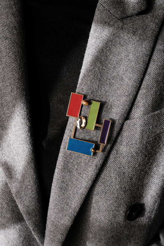 Suzanne Tiger's eye brooch pendant featuring colorful geometric enamels on a stylish blazer.